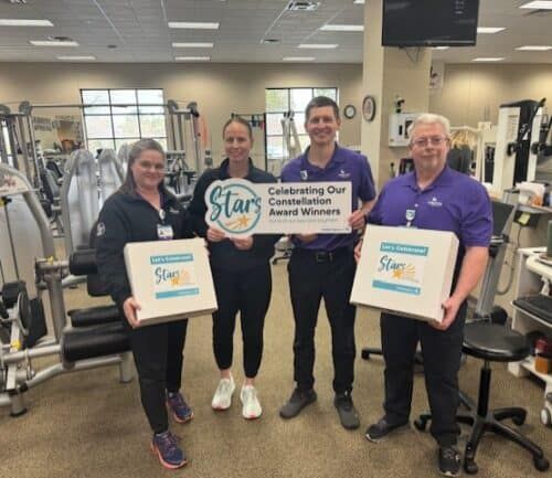 Four healthcare staff members holding Star award certificates in rehabilitation gym