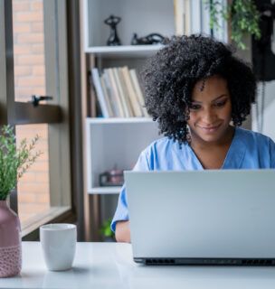 Woman in scrubs sitting in front of a computer