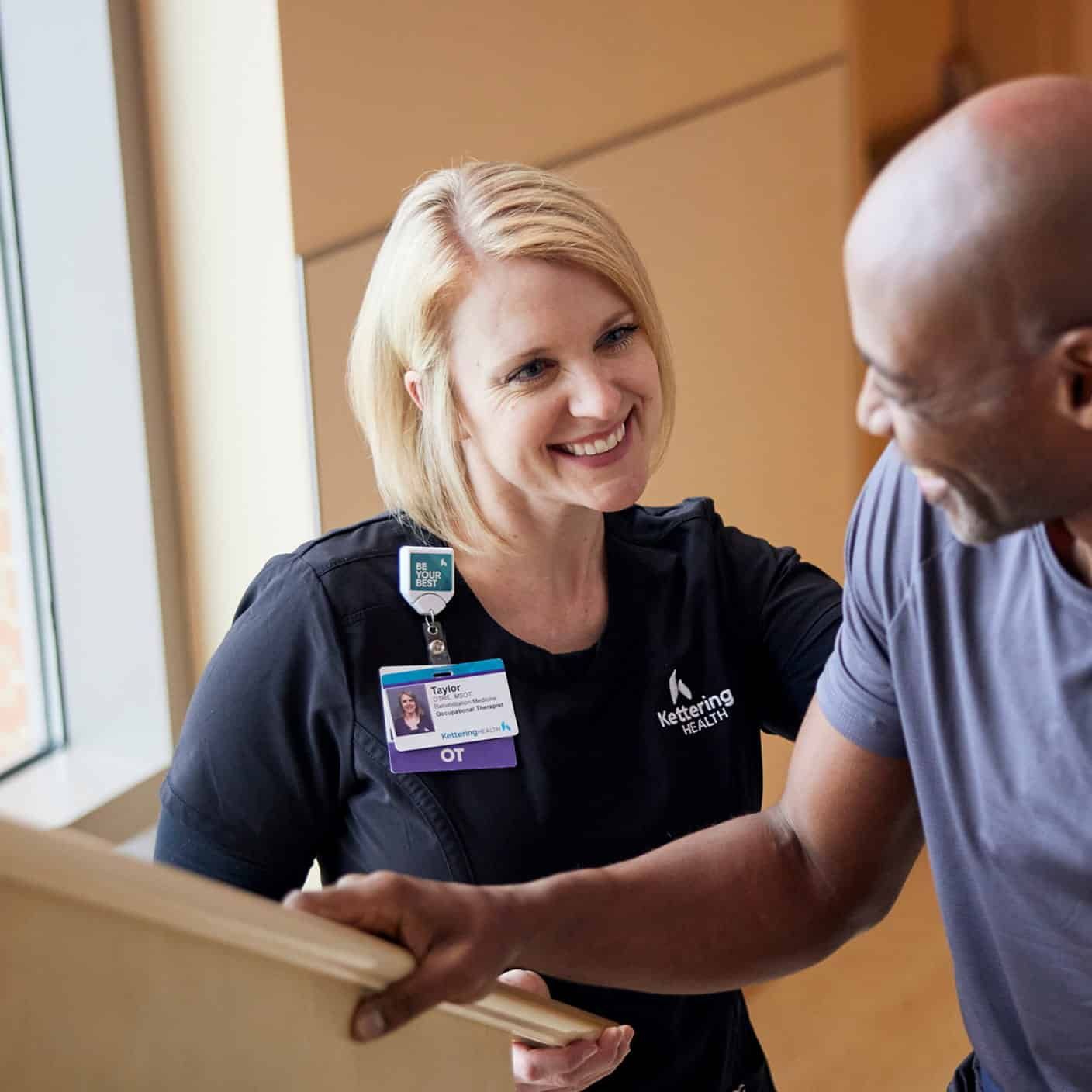 Healthcare professional Taylor, occupational therapist at Kettering Health, engaged in patient conversation.