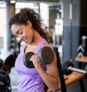 Woman lifting weights and weight training at the gym