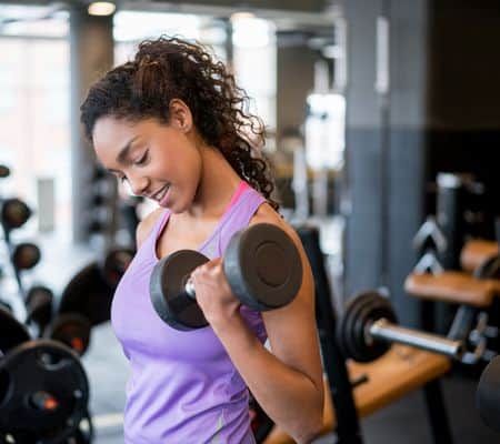 Woman lifting weights and weight training at the gym