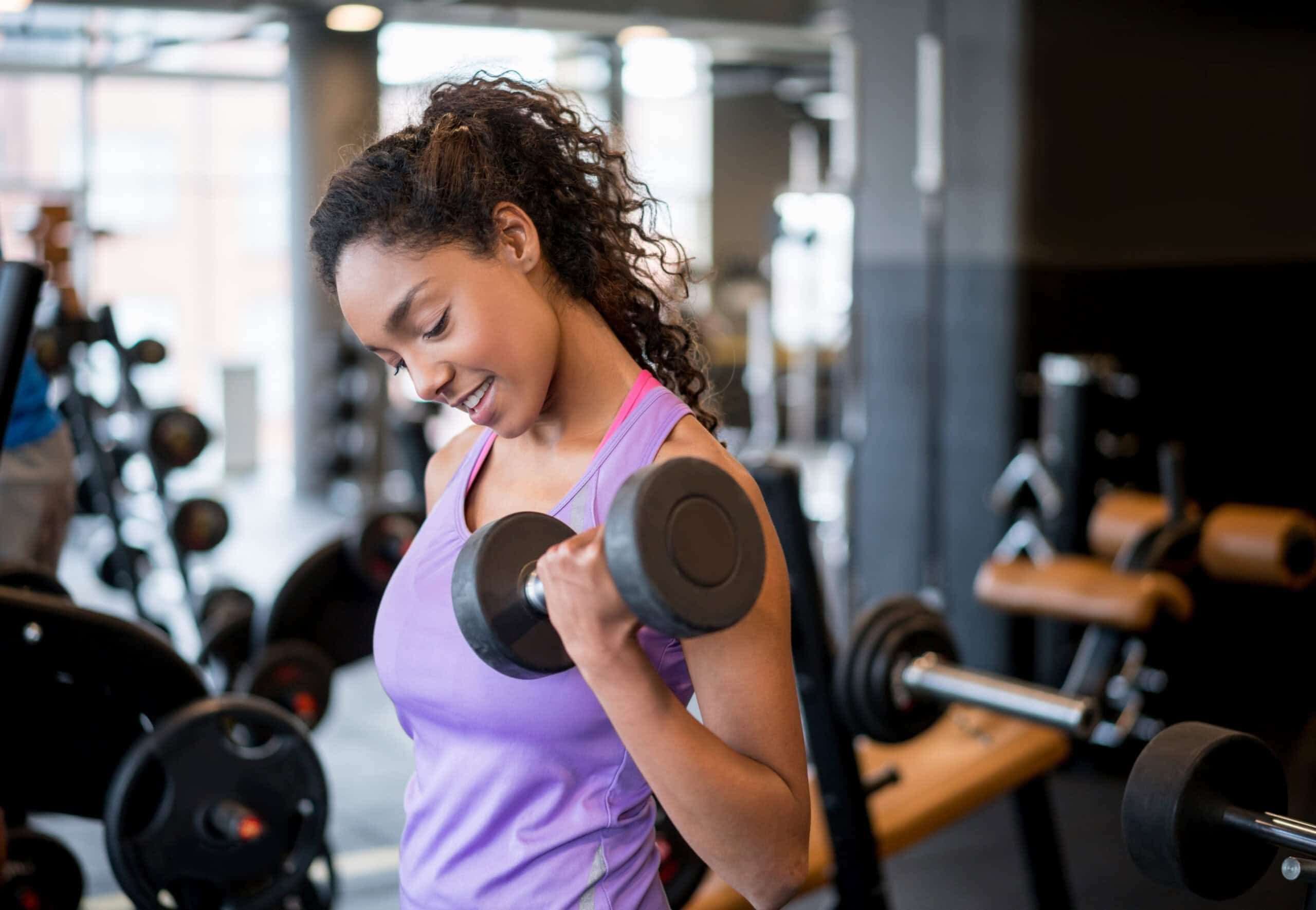 Woman lifting weights and weight training at the gym