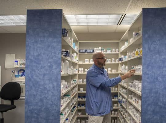Pharmacist picking medicines off a shelf