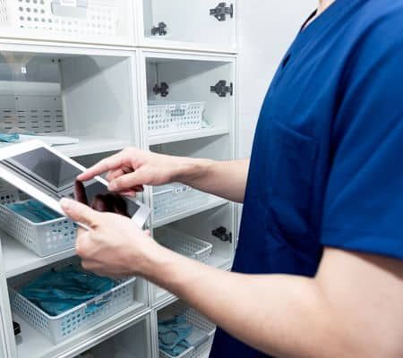 Male nurse searching something in operation room cabinet. men healthcare professional wearing medical scrubs and surgical cap looking cabinet in surgery room.