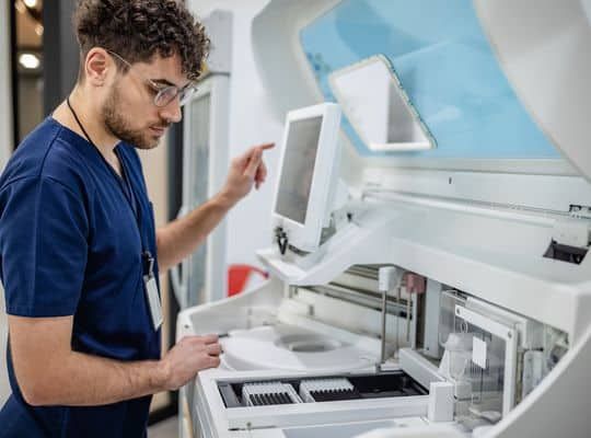 A lab technician operates advanced medical equipment in a laboratory setting, showcasing the precision and focus required for scientific research and analysis.