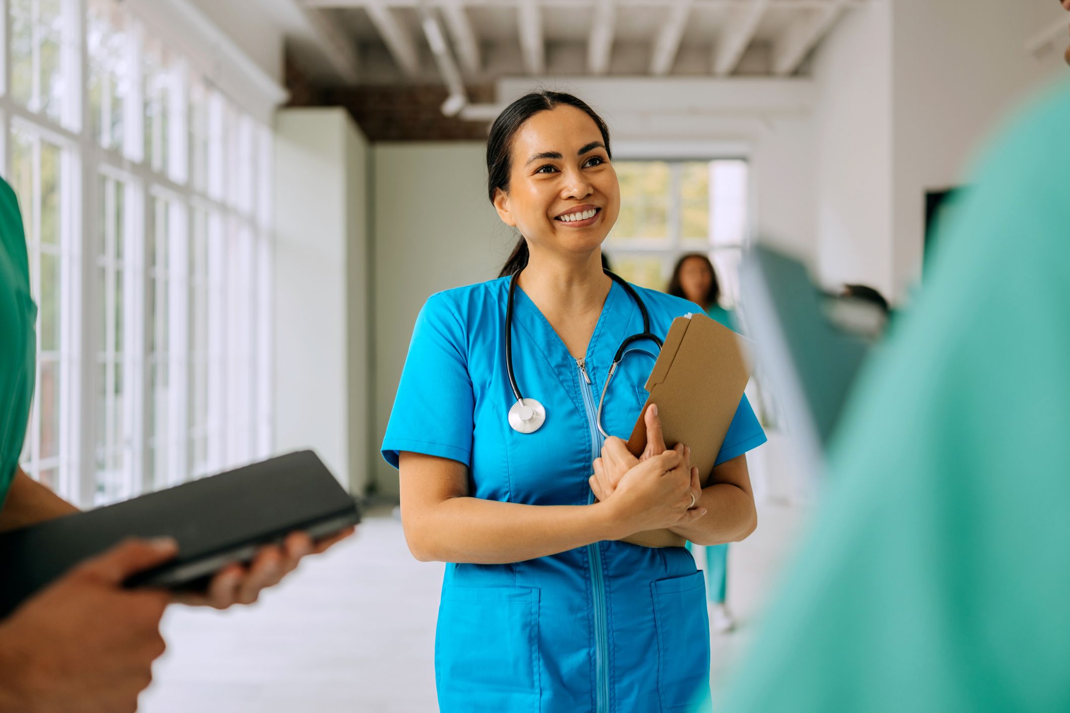 Smiling female doctor talking with her colleagues at the hospital corridor