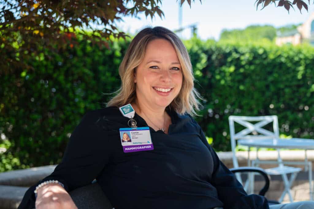 Camie Herrst, mammographer, sitting outside on bench smiling at camera