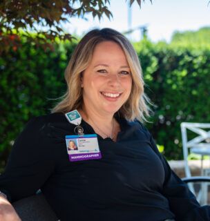 Camie Herrst, mammographer, sitting outside on bench smiling at camera