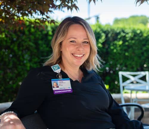 Camie Herrst, mammographer, sitting outside on bench smiling at camera