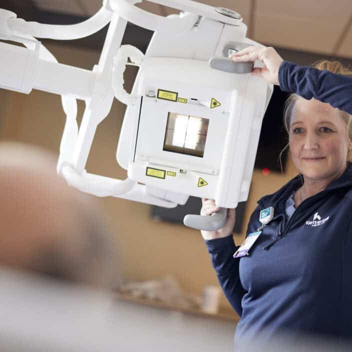 imaging specialist helping with an x ray machine