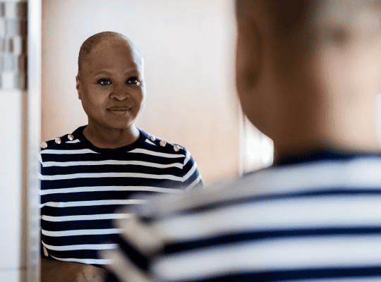 oncology patient looking at themselves in a mirror