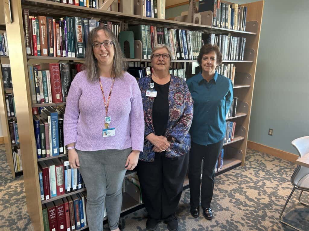 Kettering Health Medical Librarians standing in front of bookcases