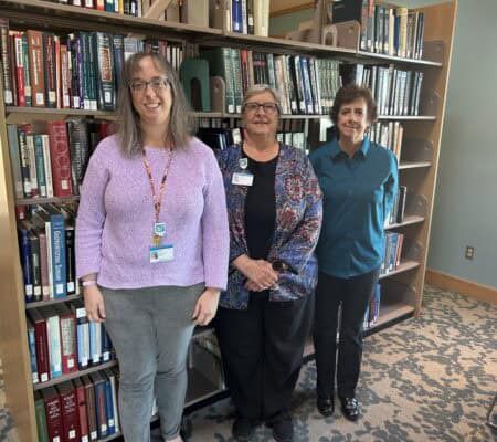 Kettering Health Medical Librarians standing in front of bookcases